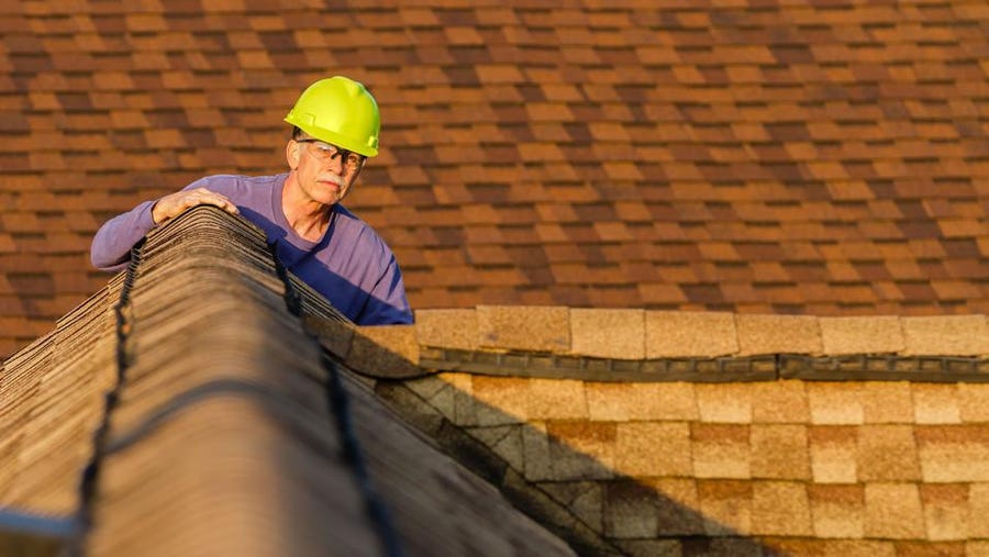 Professional inspecting an asphalt roof.