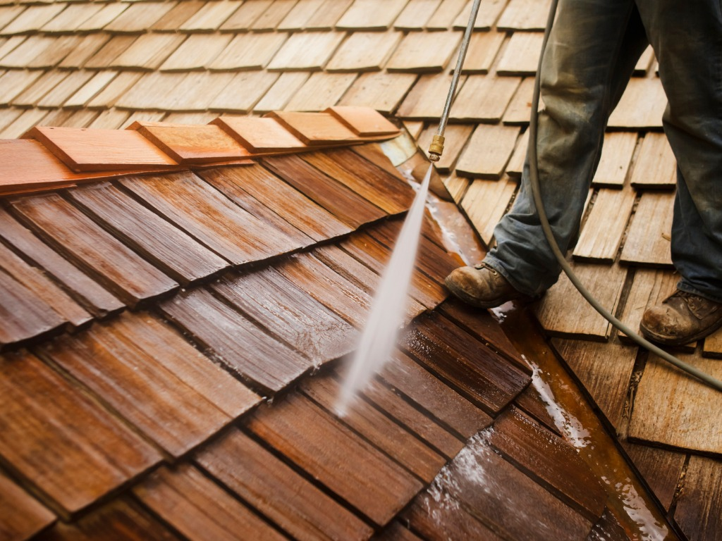 Professional power washing a cedar shake roof.