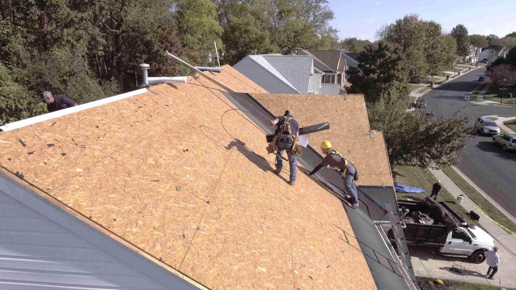 Roofing contractors installing ice and water shield over roof decking. 