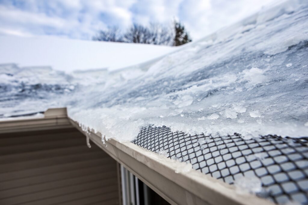 Close up of an ice dam covering a mesh gutter guard in the winter. 