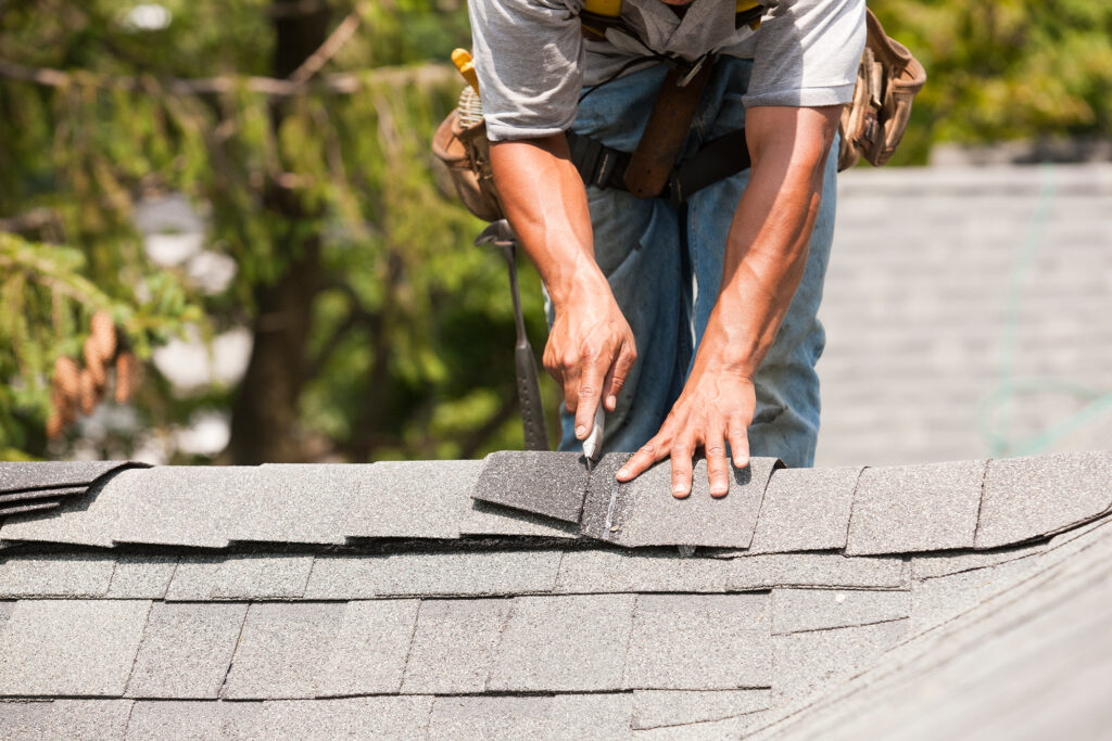 A roofer installing asphalt hip and ridge caps. 