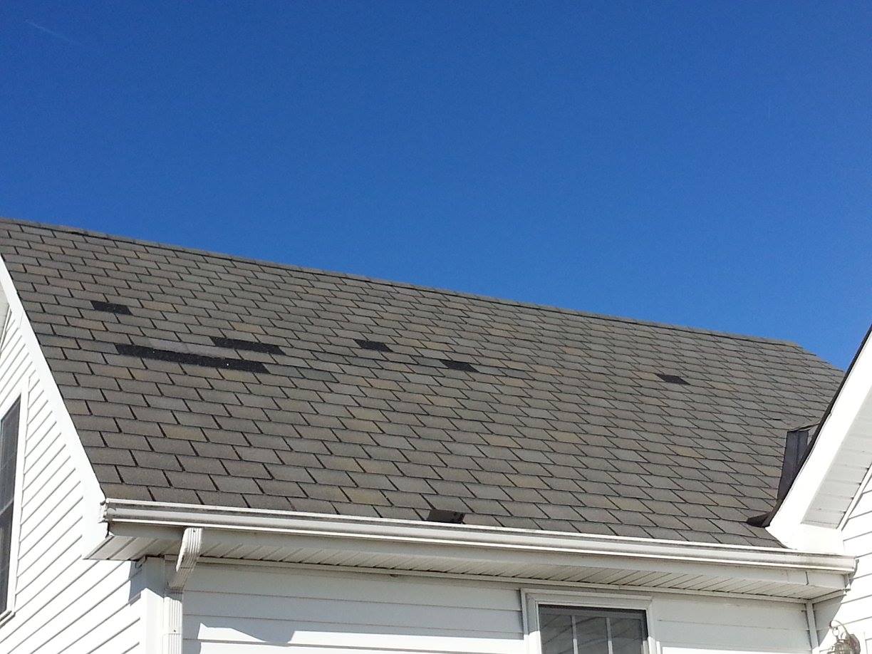 Gray asphalt roof with prominent missing shingles.
