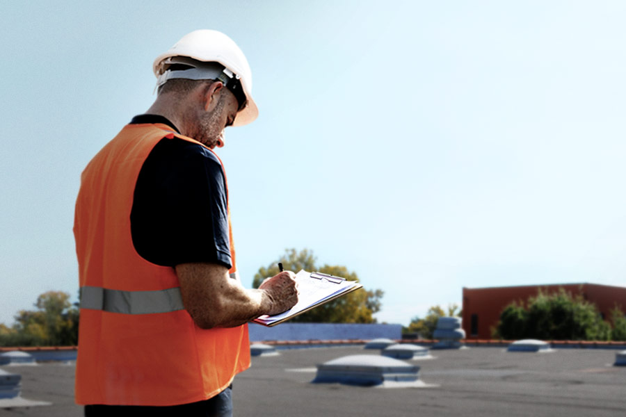 Roof inspector with a clip board inspecting a flat roof.