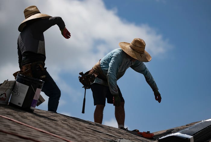 Roofers wearing hats to protect themselves from the sun. 