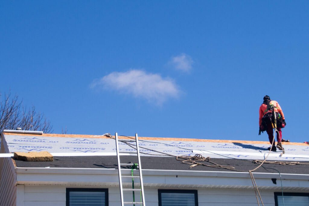 Lone roofer standing on a torn-off asphalt roof with ice and water shield.